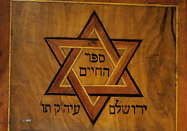 Hebrew book with wood cover with inlaid design and carving. Carved temple at bottom front, above is an inlaid Star of David.