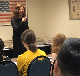 Photograph of a red headed female leading a classroom of students.