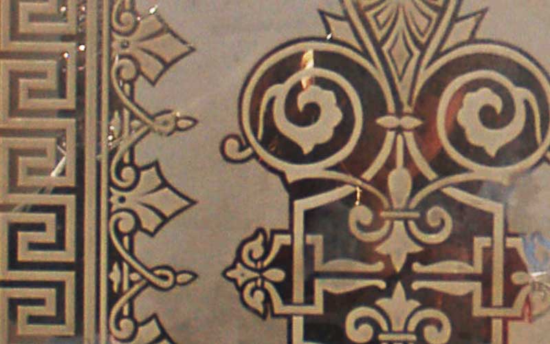 Closeup of the engraved glass on the door. Shows french style patterning with curves and hard edges.