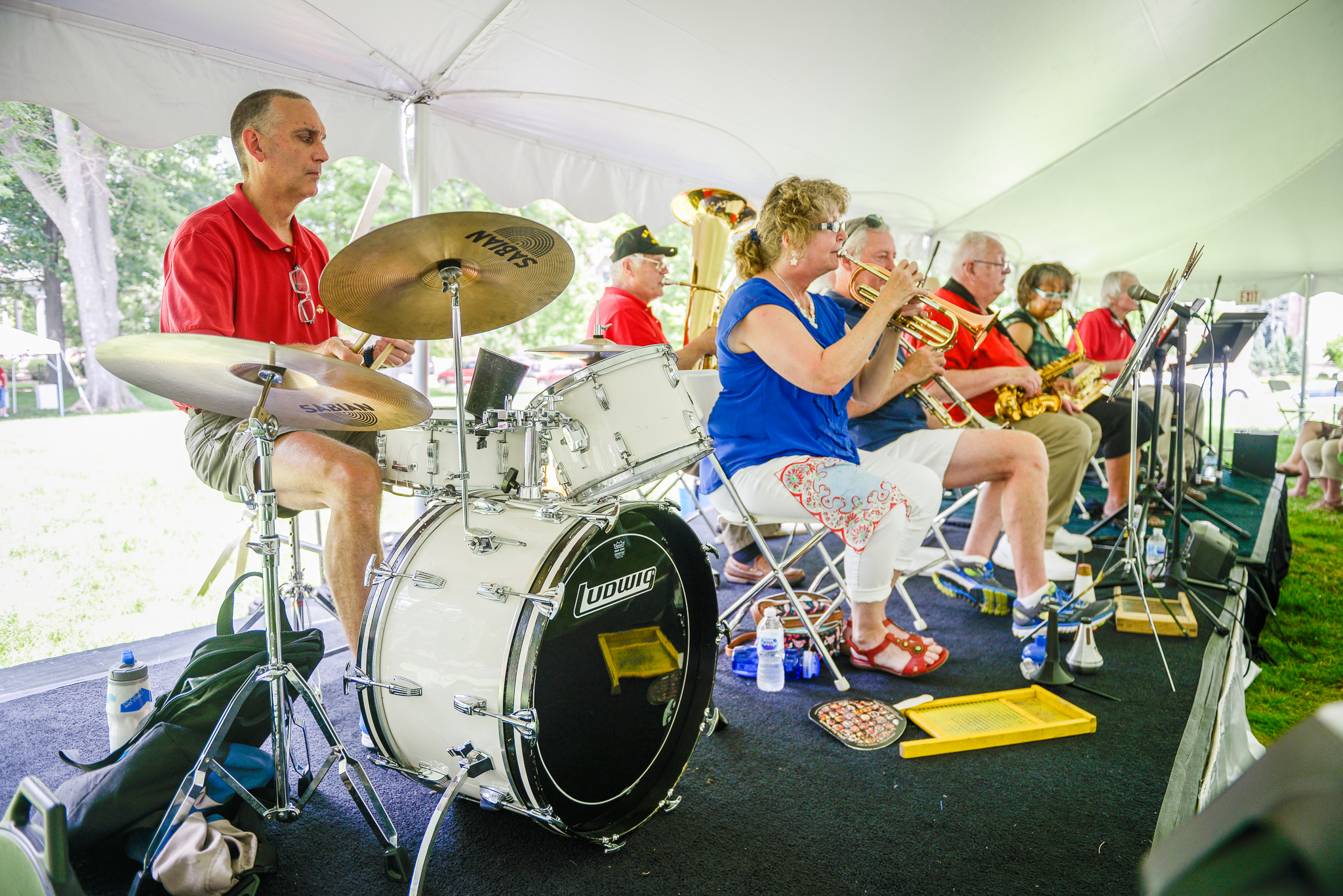 photograph of a live band performing at a presidential site event. band includes a drummer and a brass section.