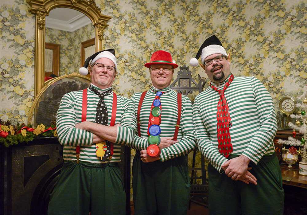 Photo of three men dressed as festive elves during a holiday event at the candlelight theater.